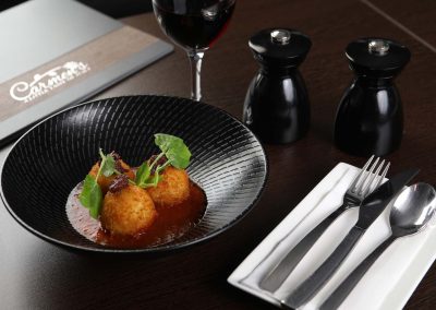 Croquettes served in a black textured bowl.