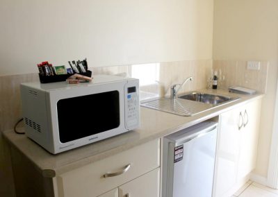 Kitchenette at Stockman's Motel. A microwave is on the benchtop to the left and there is a fridge under the counter.