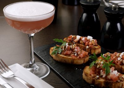 Bruschetta with tomato and feta topping and a refreshing cocktail
