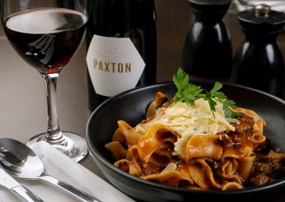 A delicious looking plate of pasta with a glass of red wine